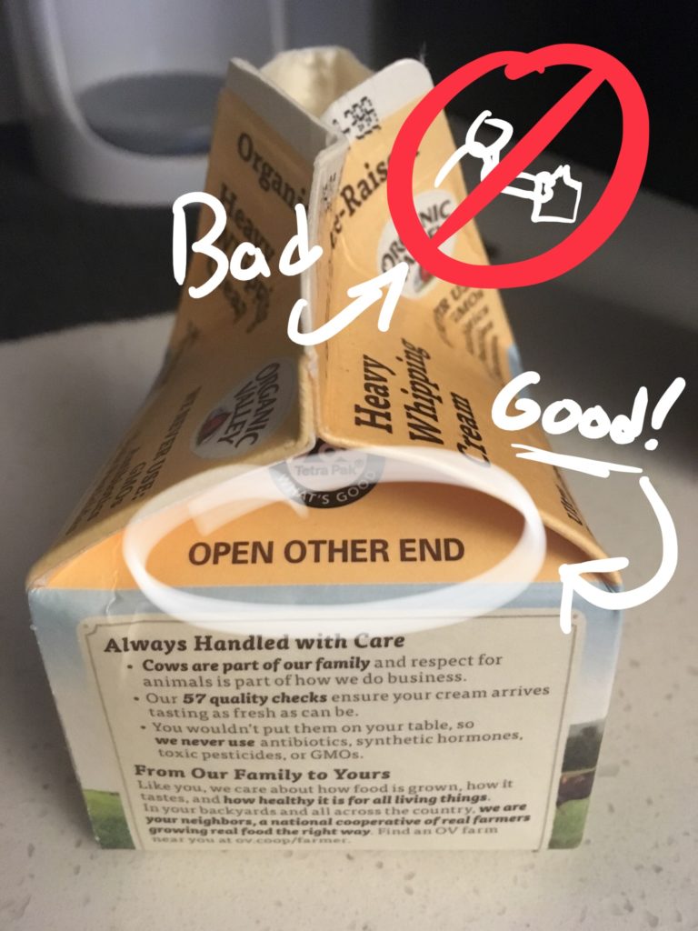 A paper cream carton with text that reads OPEN OTHER END on the side you're not supposed to open.